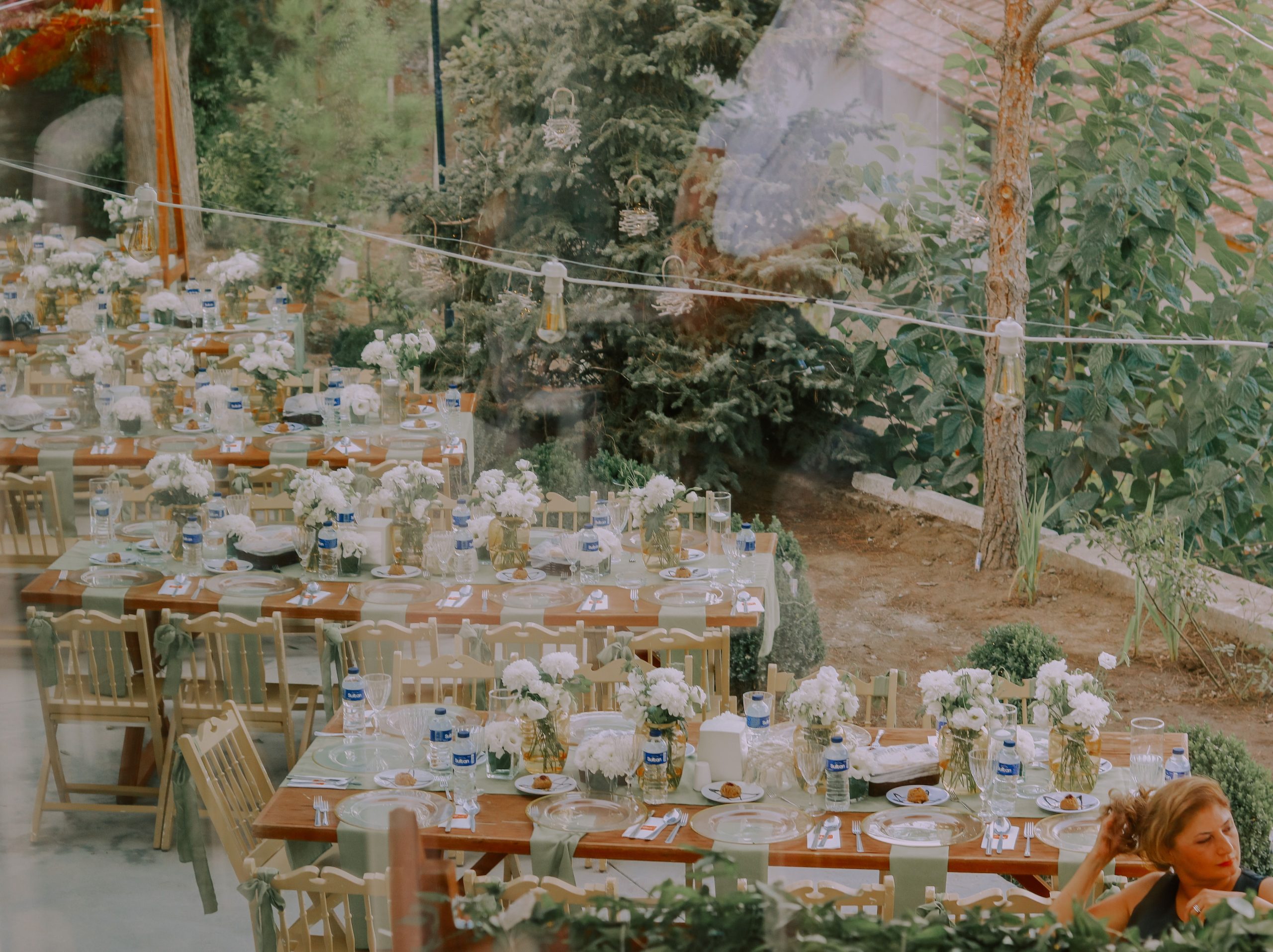Réception de mariage en extérieur avec tables en bois et décoration florale